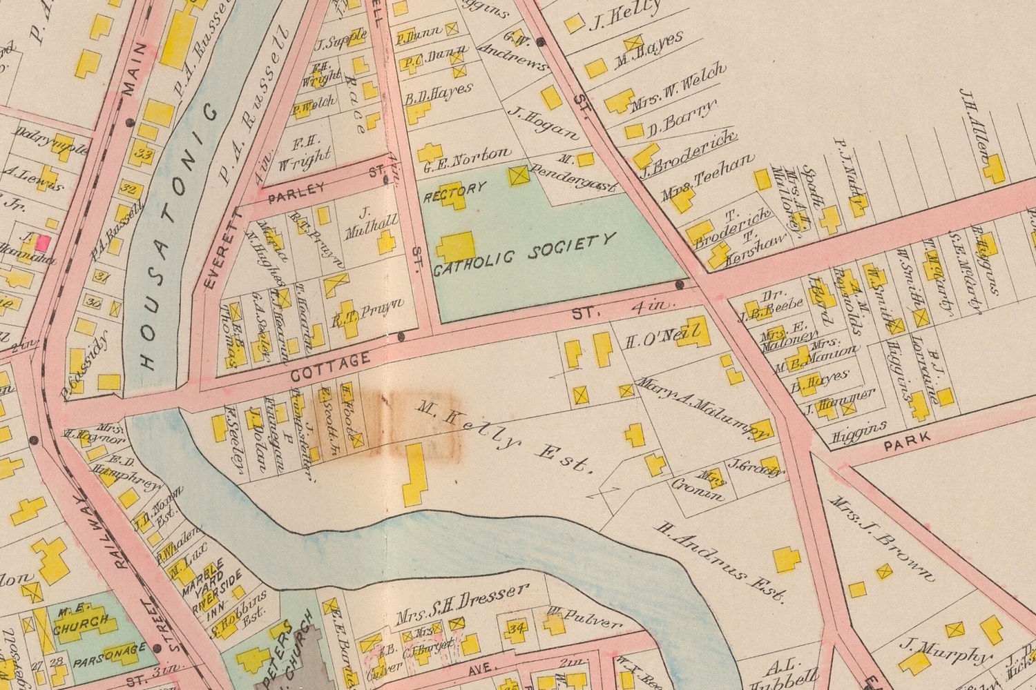 Plate 34: Cottage Street at the Housatonic. The triangle north of Cottage Street, between Everett, Parley and Russell, is small wooden houses and barns — E. E. Thomas, G. A. Seeley, T. Hearn, M. Hughes, B. T. and R. T. Pruyn, J. Mulhall, F. H. Wright, P. Welch, J. Supple — with the mill race lettered along it. South of Cottage Street, six narrow lots front the river: R. Seeley, J. Dolan, P. Finnegan, J. Hungpstetter, E. Scott Jr., H. Foote. East of them the open M. Kelly Est. Nothing here is lettered rubber, mill, works, factory or Stanley.