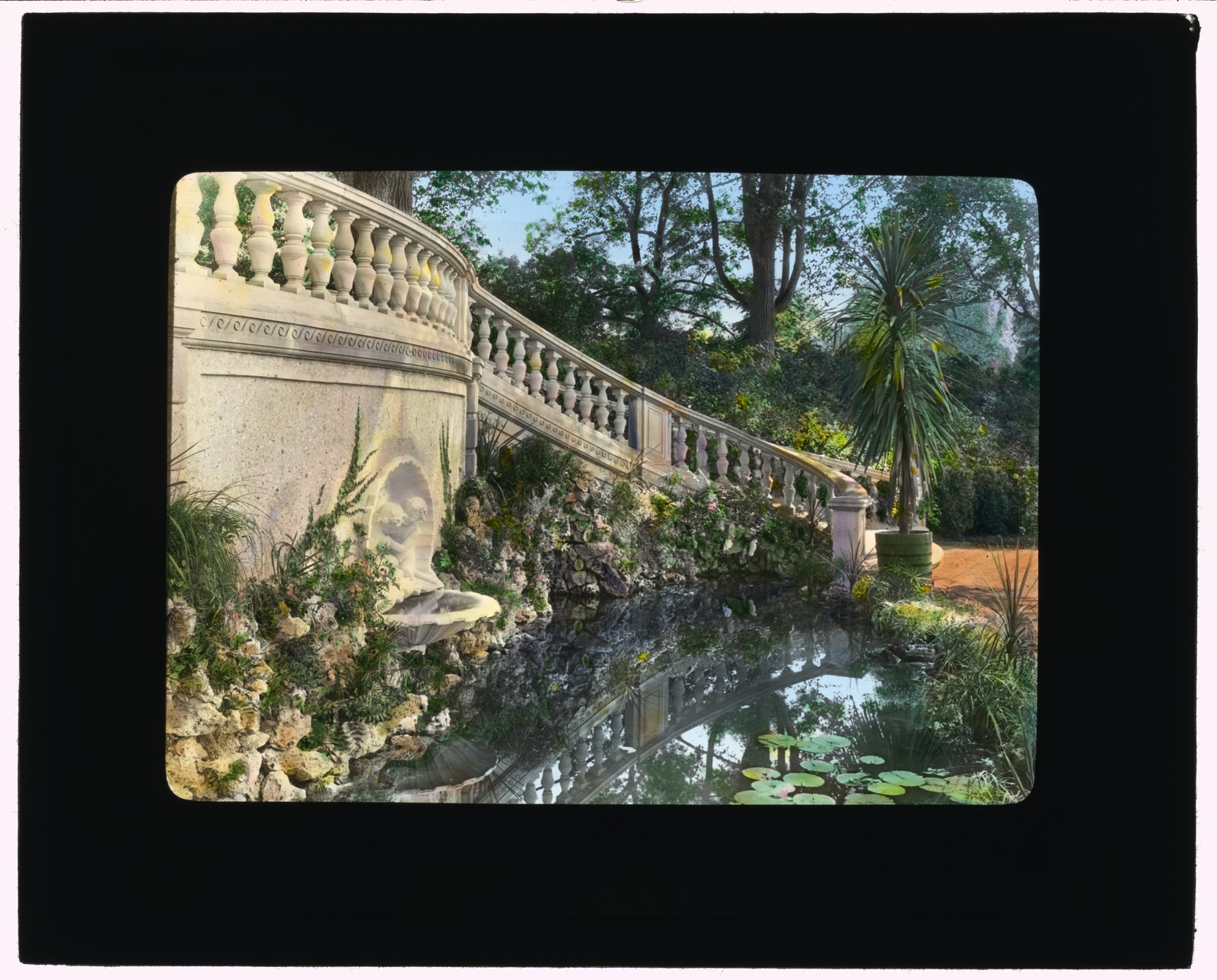 “Wall fountain.” The balustrade above a lily pool, with a mask fountain set into the wall below it.