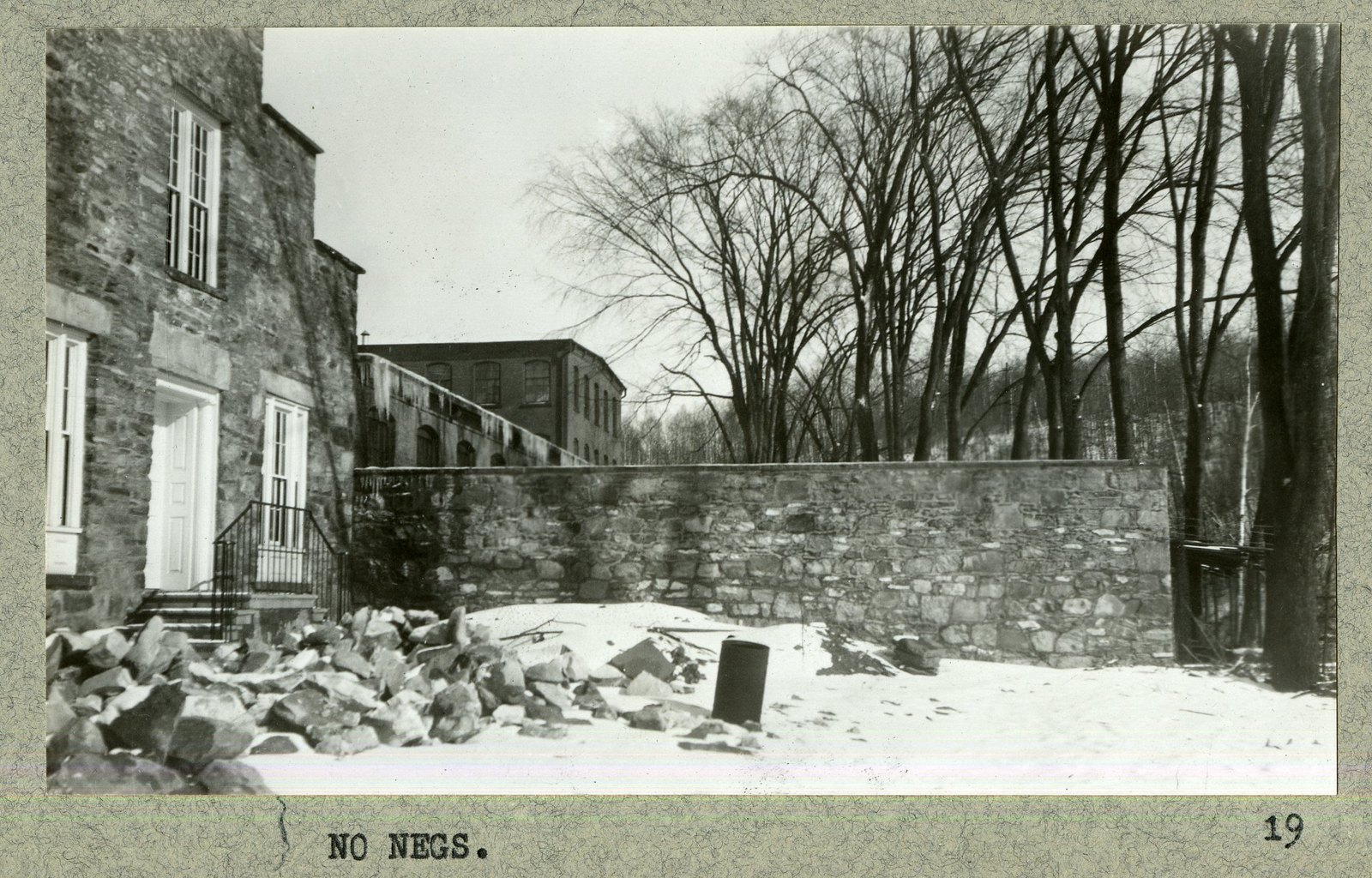 The wall under construction, stone still stacked on the ground. The mount is captioned “NO NEGS.”