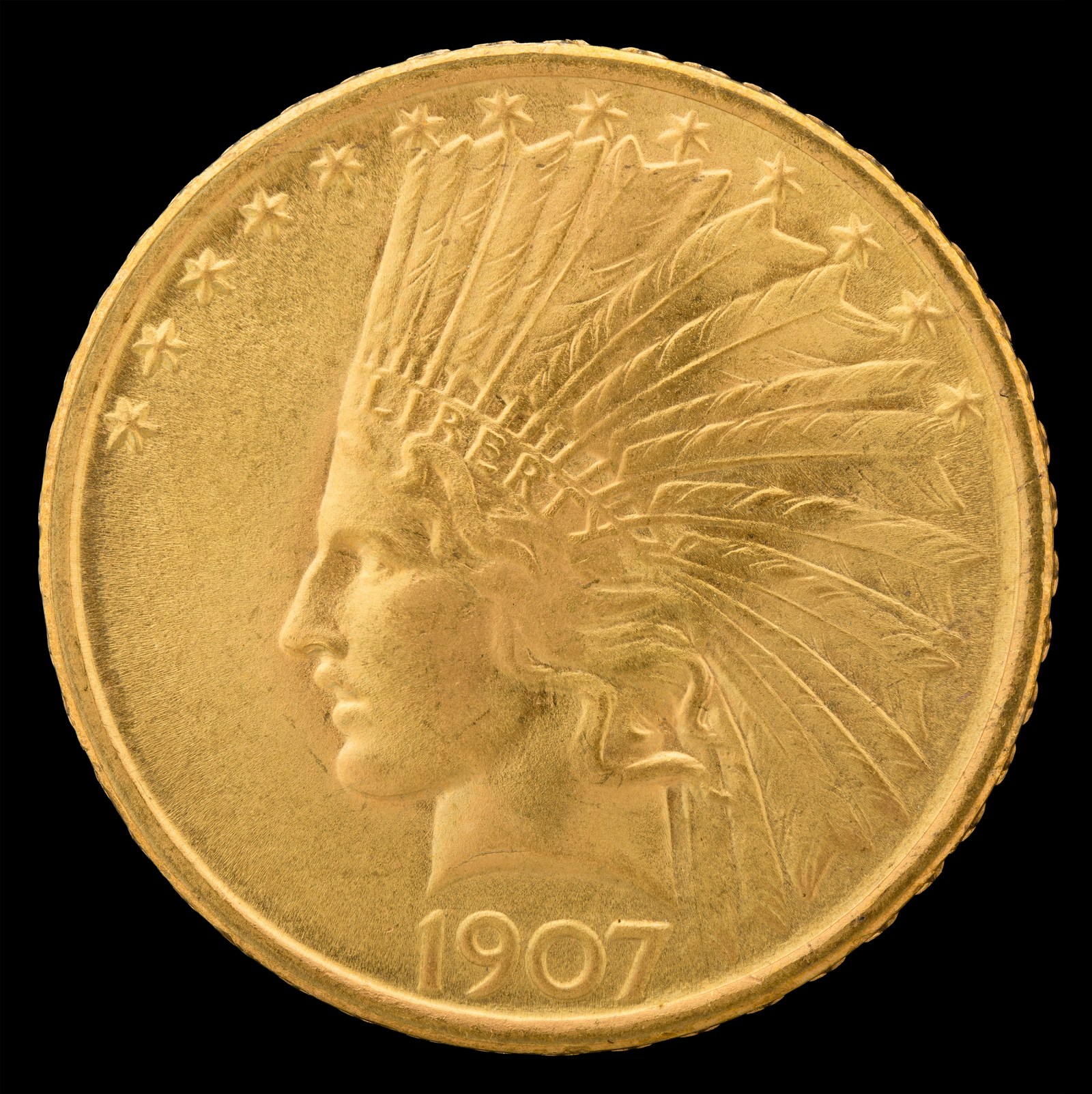 The Indian Head eagle, $10, 1907. Roosevelt asked for the feather war bonnet; Saint-Gaudens put it on a classical Liberty, which is a stranger object than it first looks.