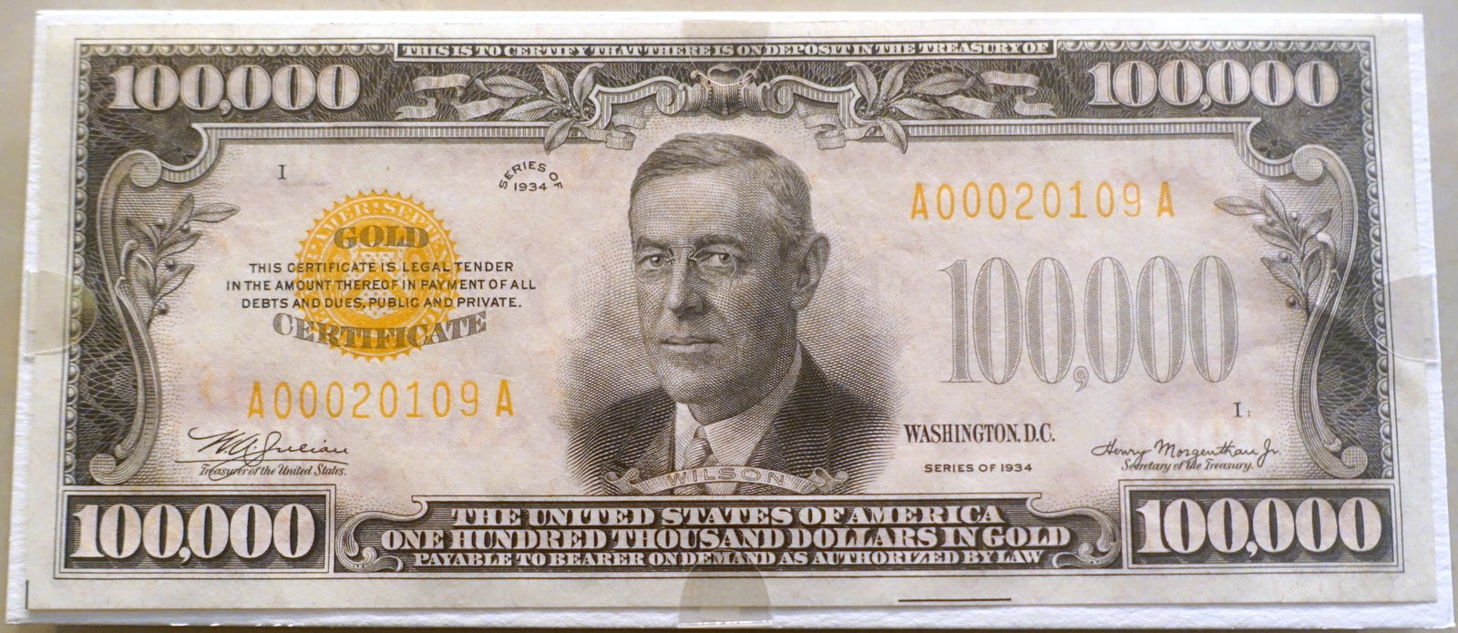 One hundred thousand dollars, gold certificate, Series 1934, as displayed at the National Museum of American History. The note says “payable to bearer on demand” and “legal tender”; it was never issued to anyone outside the Federal Reserve.
