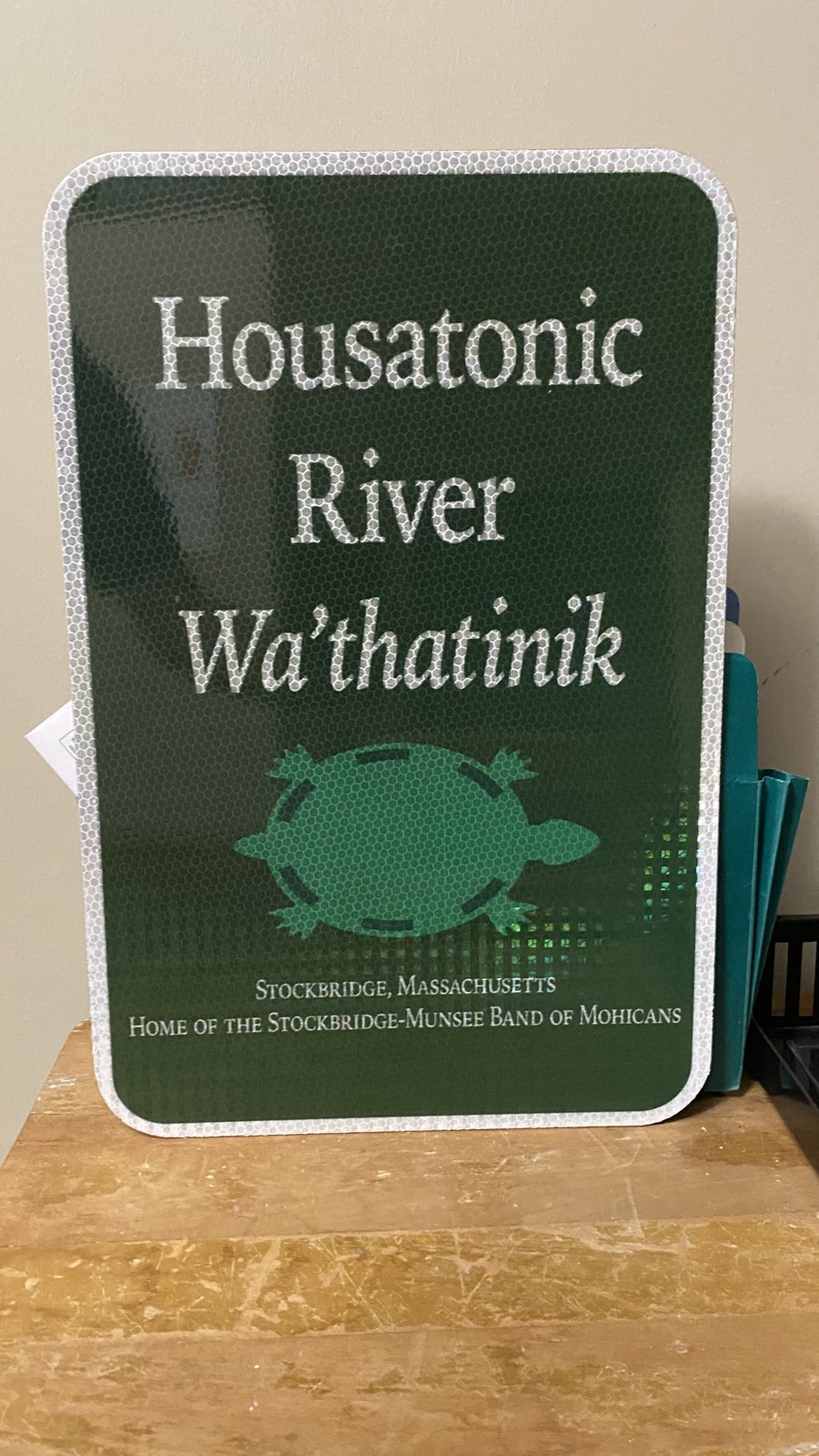 A Stockbridge road sign: HOUSATONIC RIVER / Wa’thatinik / Stockbridge, Massachusetts / Home of the Stockbridge-Munsee Band of Mohicans, with a turtle emblem.