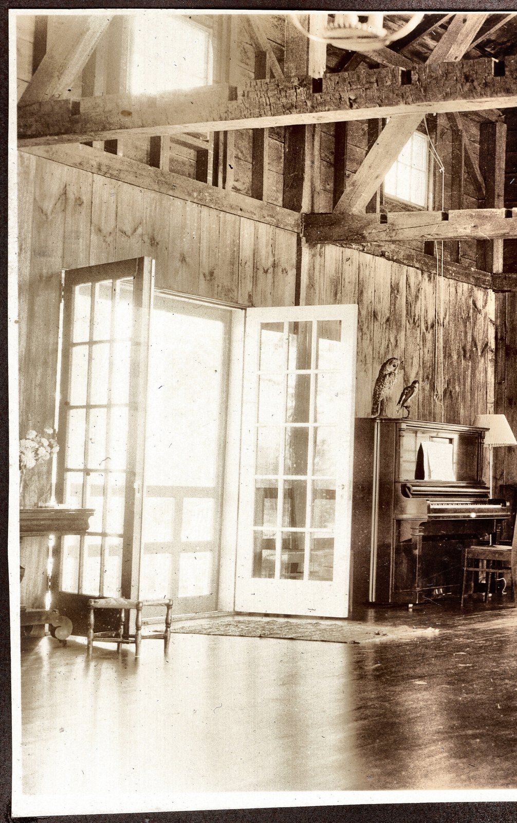 The same room from the other end, the piano in the corner and the floor bare.