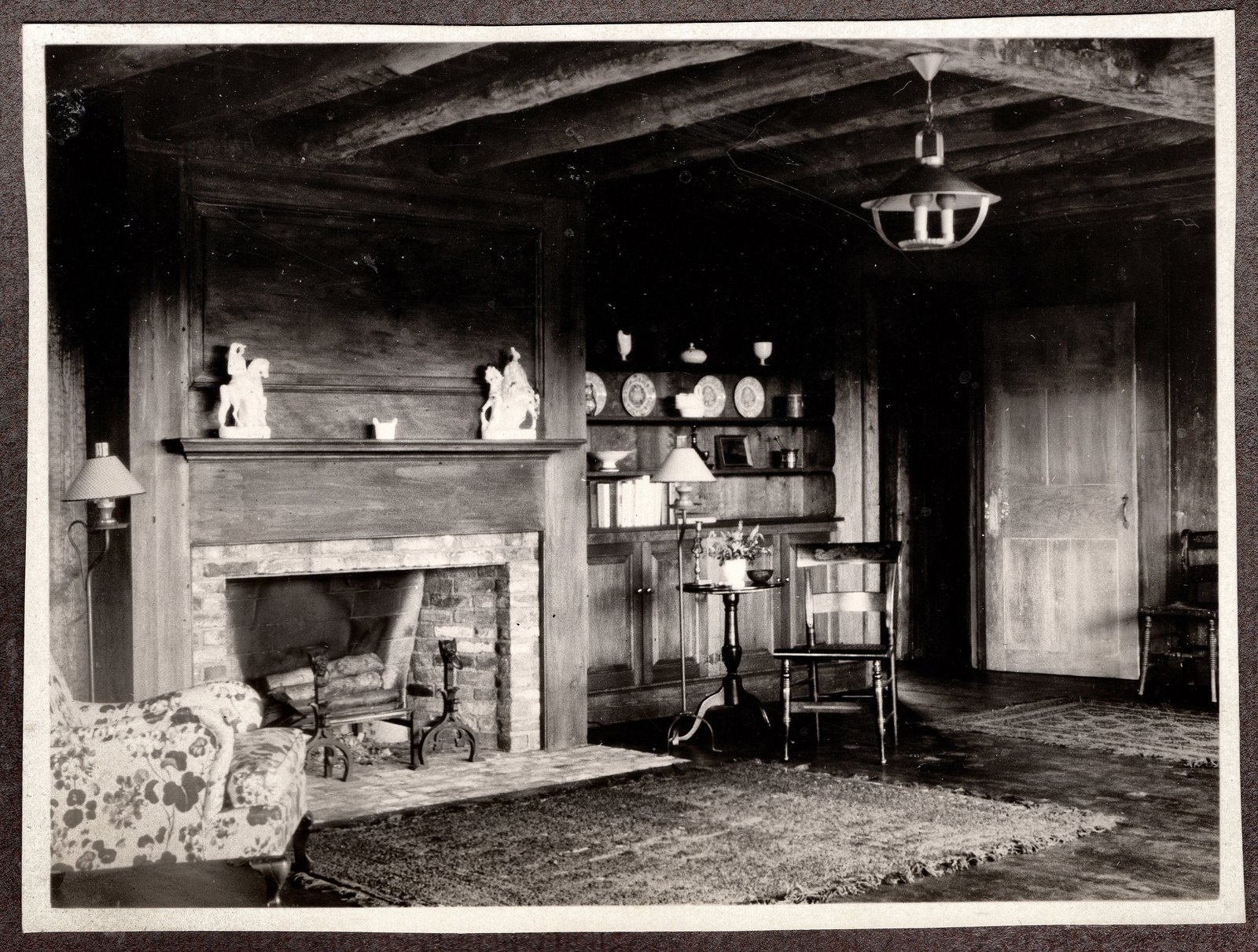 The fireplace end, with china on an open shelf and a rag rug at the hearth.