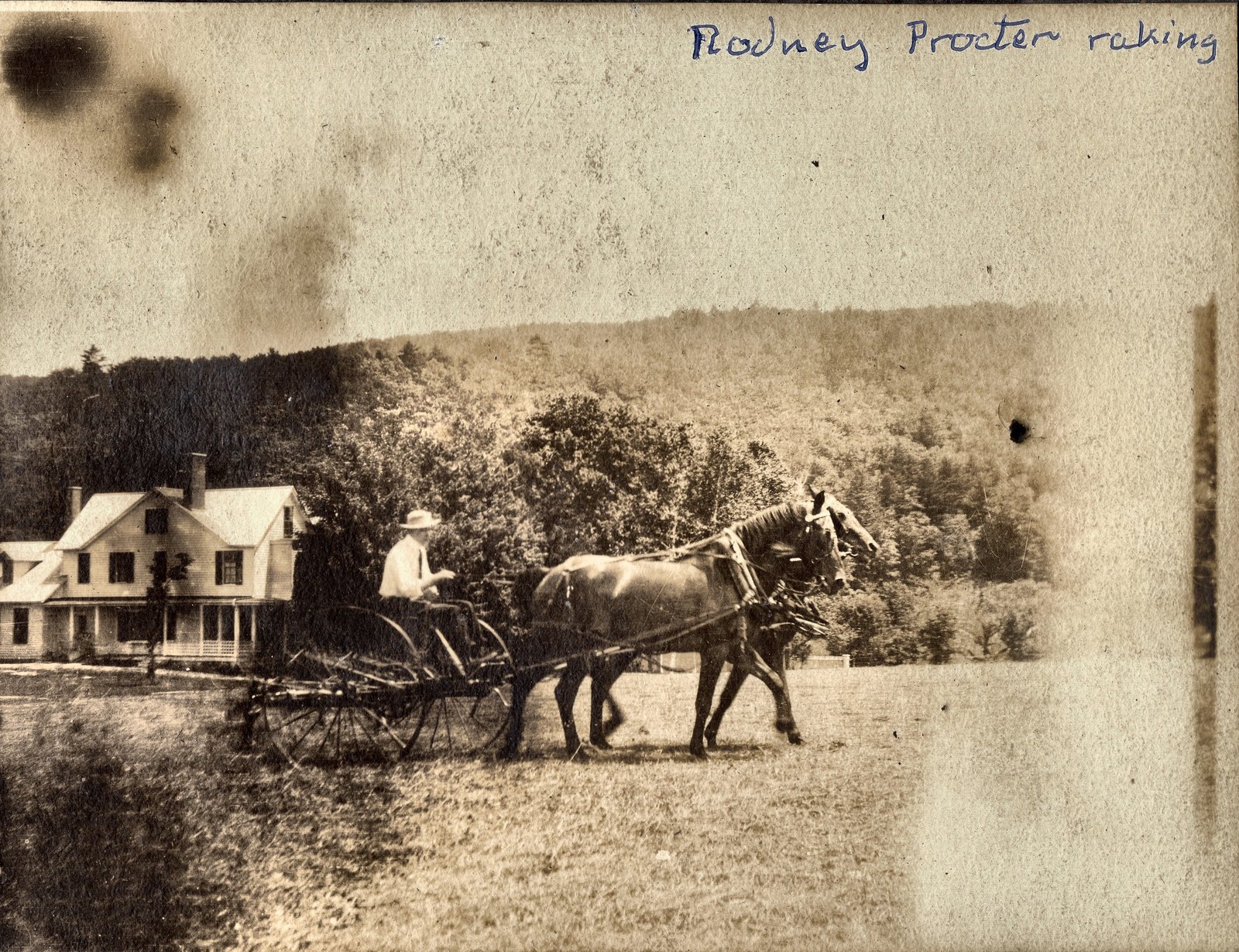 Rodney Procter raking, with the farm house behind him.