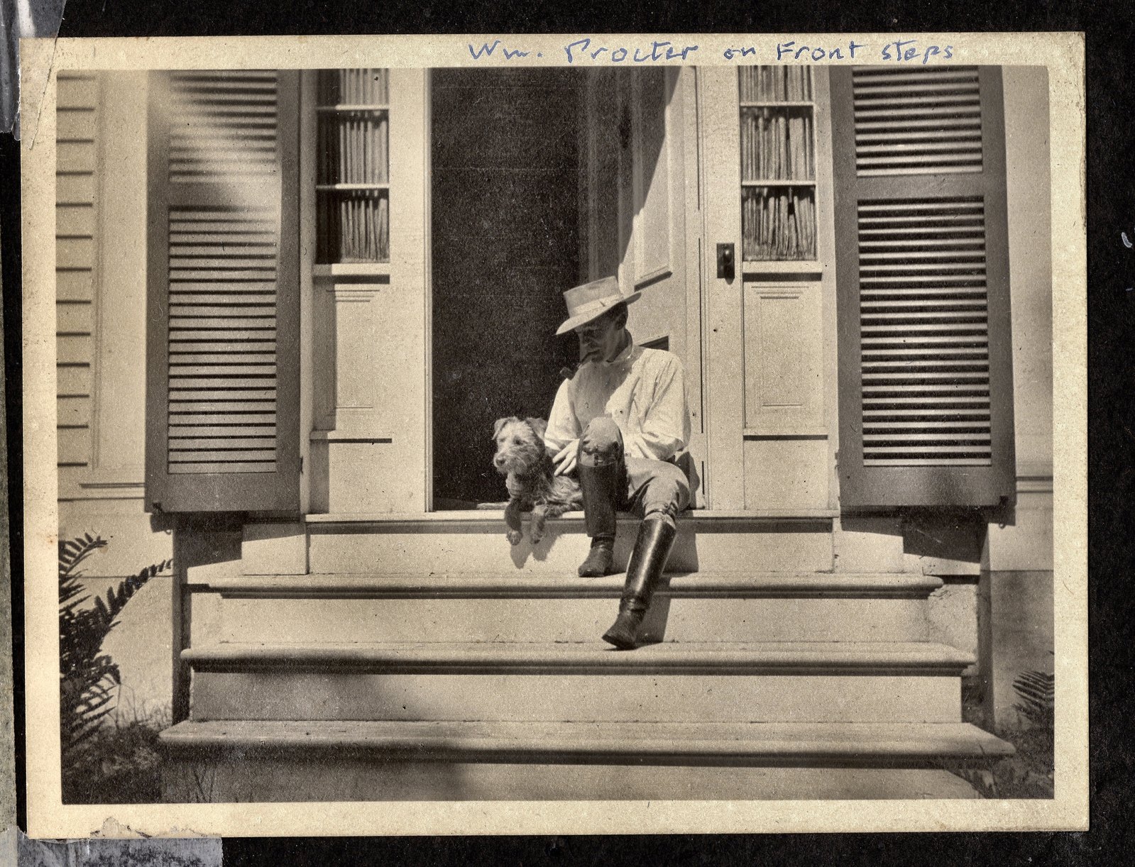 Wm. Procter on front steps — a man in a wide hat seated on the step with a dog, between the open shutters of the farm house door.