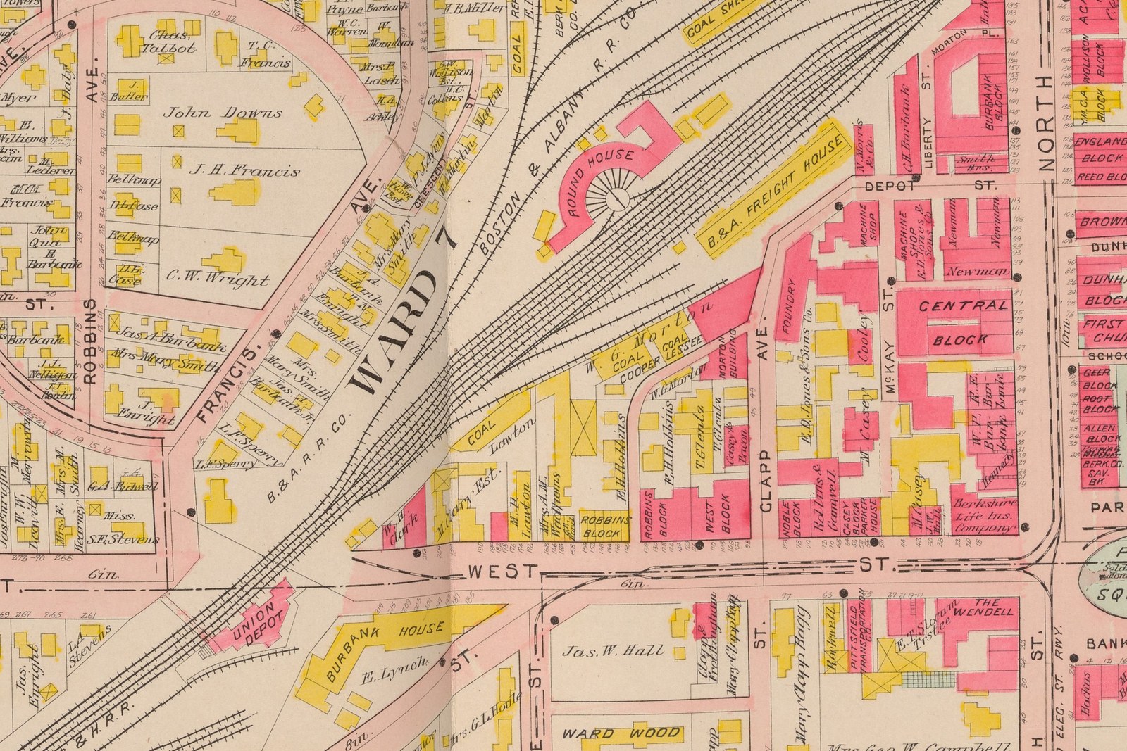 Plate 2: the Boston and Albany yard. Fifteen tracks fanning across the sheet, the brick ROUND HOUSE with its turntable and radiating stalls, the long wooden B. & A. FREIGHT HOUSE beside it, and four separate coal dealers along the edges of the yard — C. C. Gamwell, E. P. Wood, W. G. Morton and Lawton, with a refrigerator house and the Berkshire Lumber Co. as lessees. UNION DEPOT is the small pink building at the lower left. The vertical shadow through the middle is the book’s gutter: this is a double-page plate.