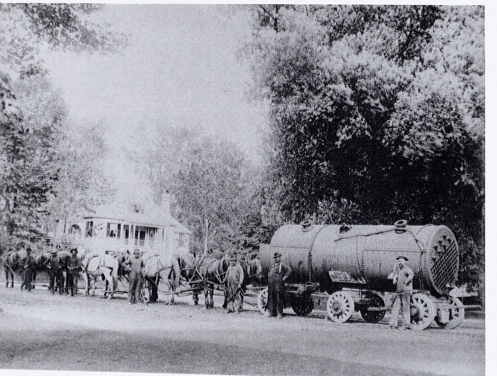 A steam boiler for the Aspinwall Hotel at the foot of Church Hill in Lenox, on a low wagon, hitched to a team of ten horses, with the crew standing alongside. This is what installing central heating looked like before it was in the cellar.