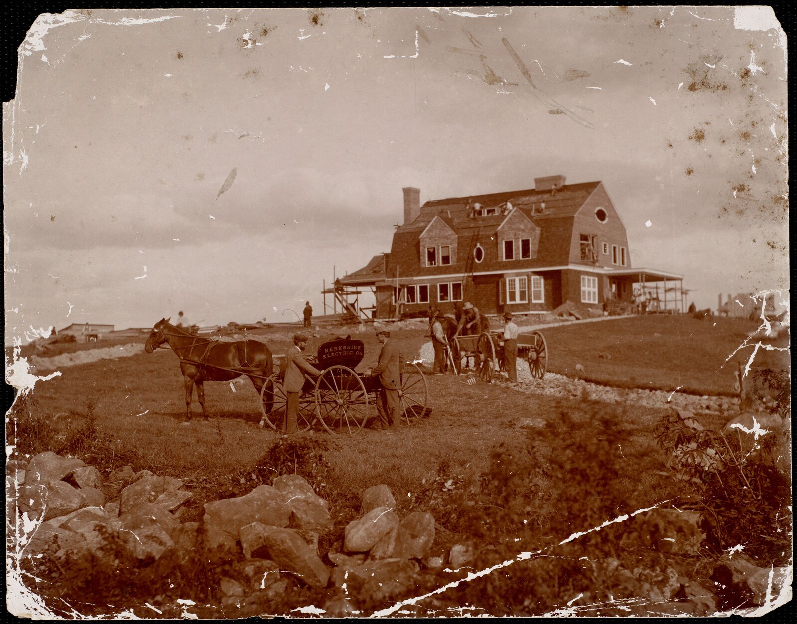 BERKSHIRE ELECTRIC CO., lettered on the side of a buggy, parked in front of a house that is not yet roofed. The single clearest trade mark in the Berkshire photographic record, and it is on a wagon.