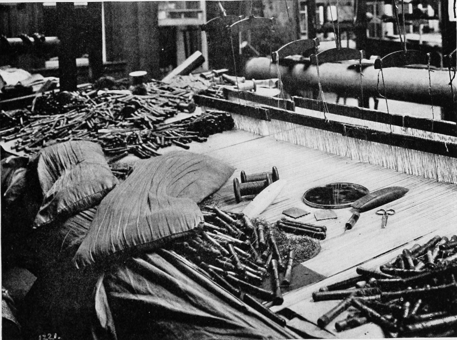 From the weaver’s point of view: the warp under the hand, the bobbins lying in the trough, the small comb, the large comb, the awl and the scissors. Everything needed to make a tapestry is in this photograph.
