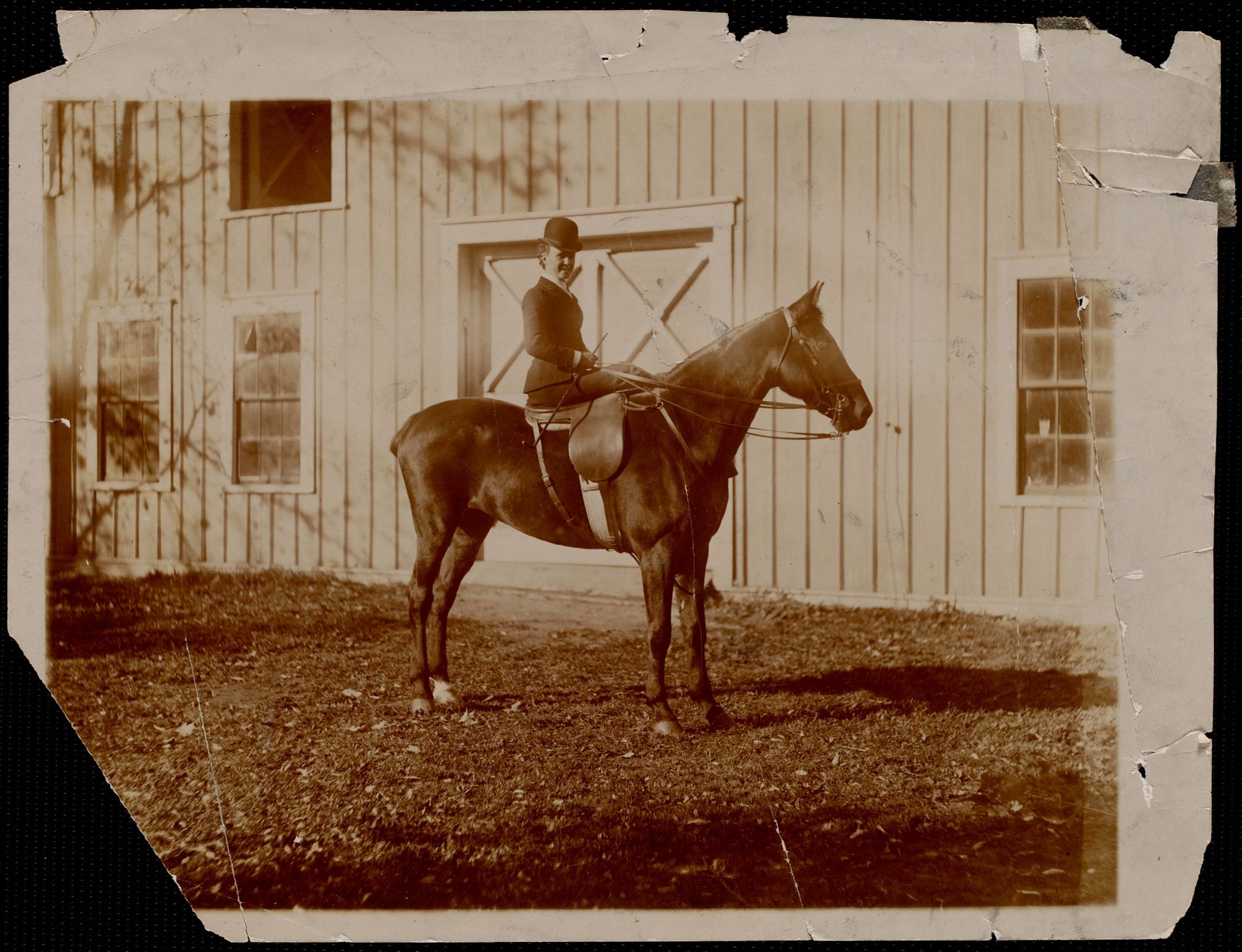 Miss Kate Cary: on horseback in front of barn door. about 1895.